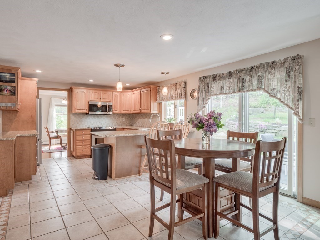 21 Scenic View Drive Pelham, NH 03076 - Photo 23 of 42 a kitchen with stainless steel appliances kitchen island granite countertop a stove a sink a table and chairs