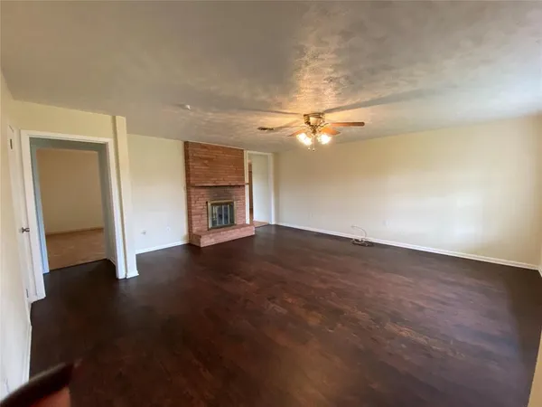 an empty room with wooden floor fan and window