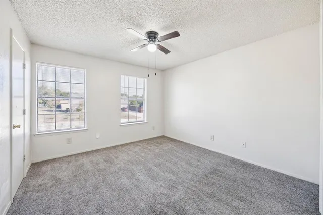 an empty room with windows and chandelier fan
