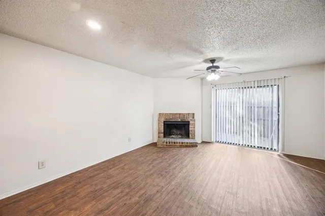 a view of an empty room with a fireplace and wooden floor