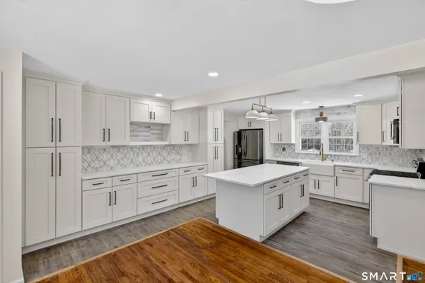 a kitchen with kitchen island granite countertop a sink a counter space and cabinets