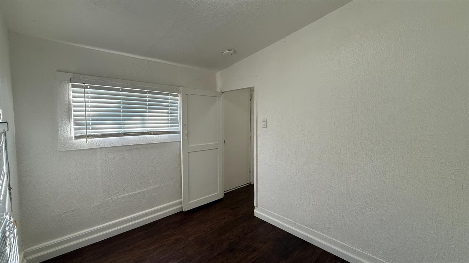 813 West 6th Street Hanford, CA 93230 - Photo 12 of 15 a view of an empty room with wooden floor and a window