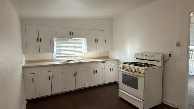 a kitchen with granite countertop white stove a sink and dishwasher