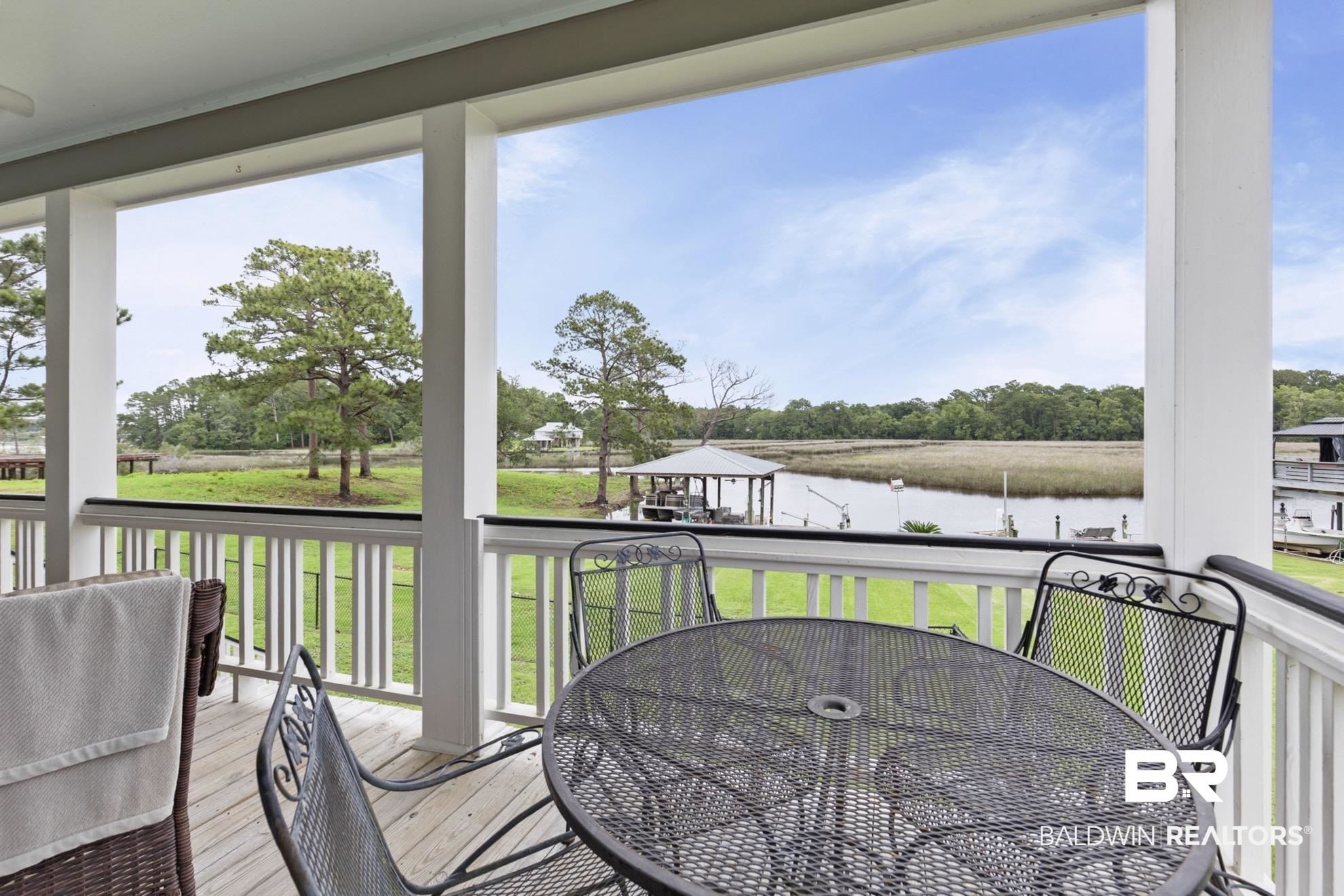 12171 Marguerite Drive Coden, AL 36523 - Photo 22 of 44 Covered porch featuring white columns and railing, providing a direct water vista with a private dock