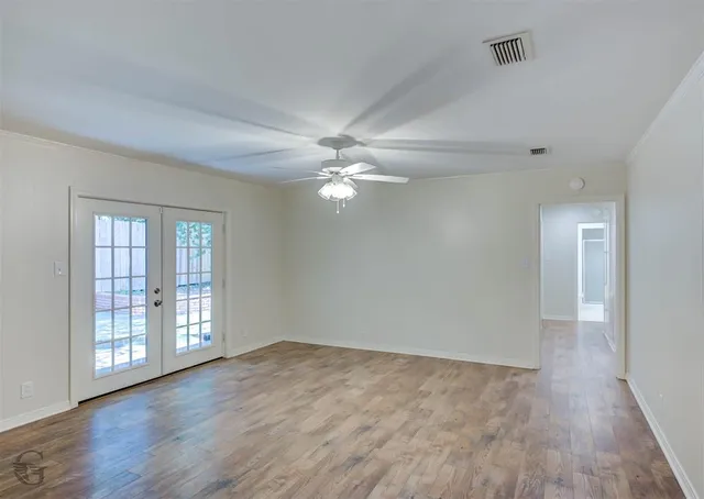 a view of an empty room with wooden floor and a window