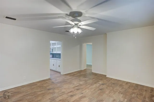 an empty room with fan and a chandelier fan