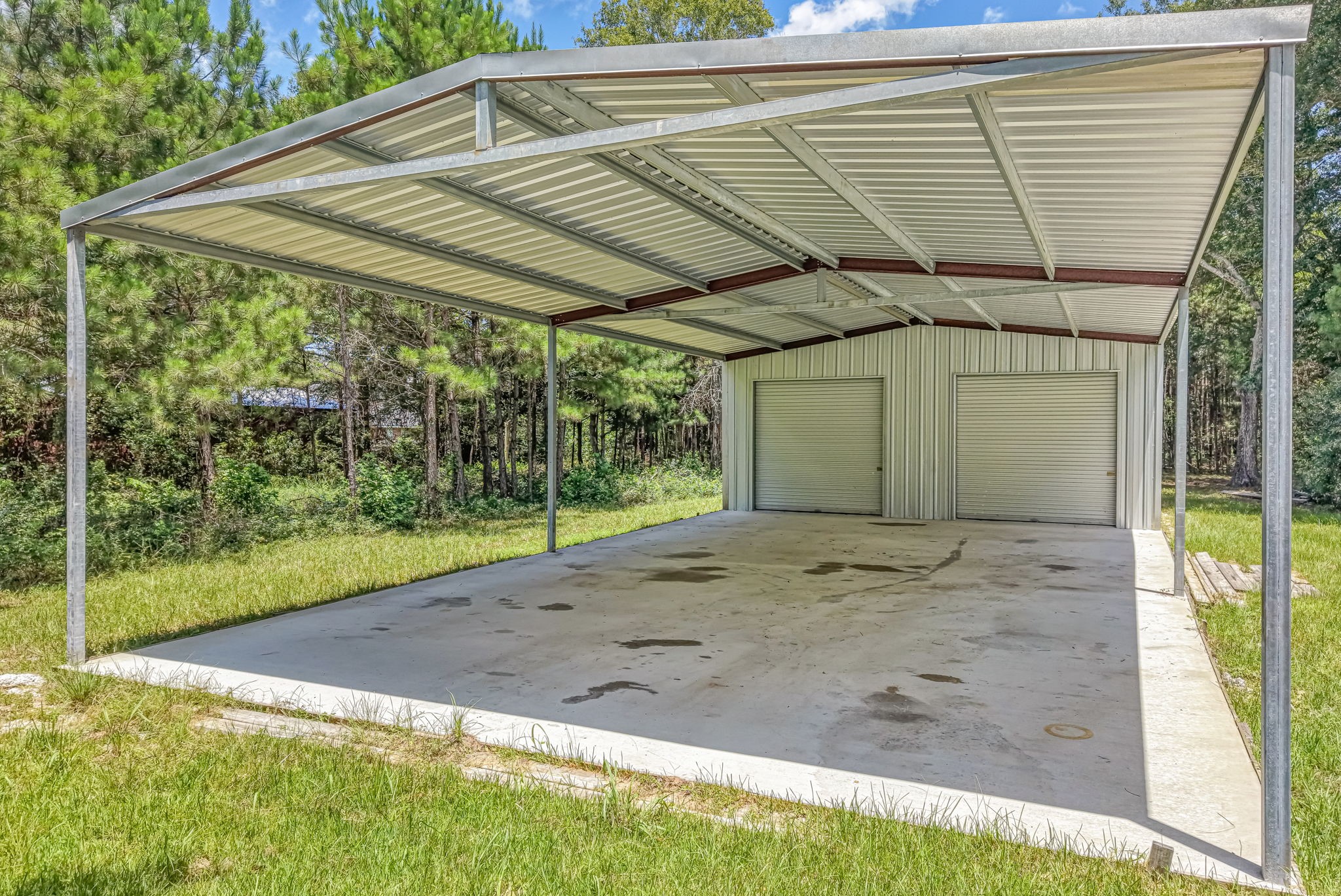 25979 Shade Tree Lane Splendora, TX 77372 - Photo 17 of 22 The metal building features a 30' x 50' enclosed workshop with two roll-up doors and a 30' x 50' covered open bay.