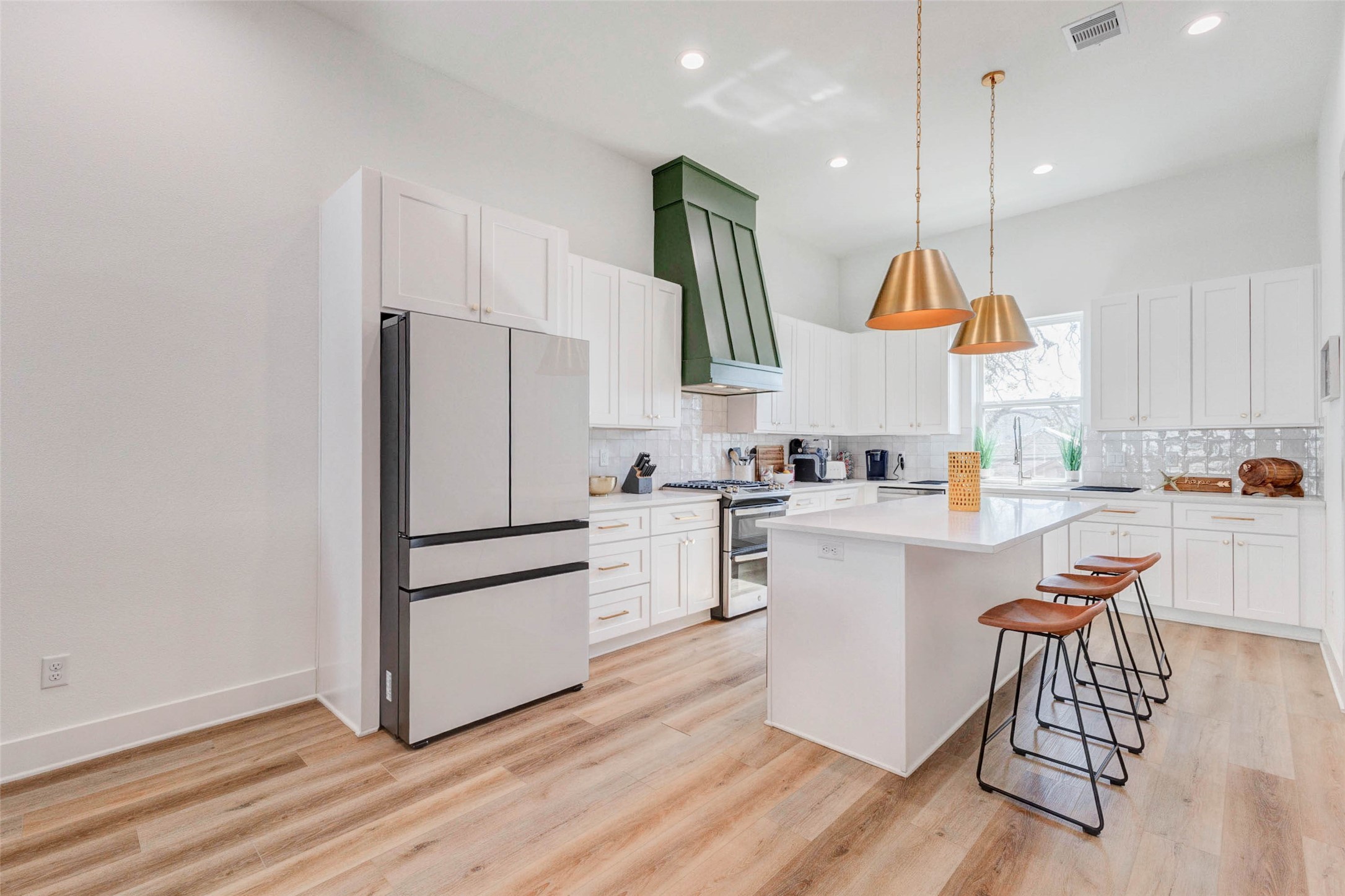 1307 East 27th Street, Unit A Houston, TX 77009 - Photo 4 of 48 a kitchen with a refrigerator a white stove top oven a sink and a dining table with wooden floor