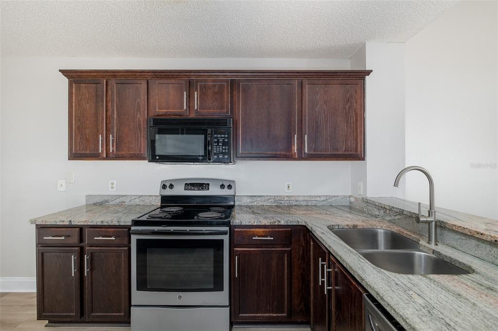 7900 Hardwick Drive, Unit 827 New Port Richey, FL 34653 - Photo 9 of 27 a kitchen with granite countertop a sink and a stove