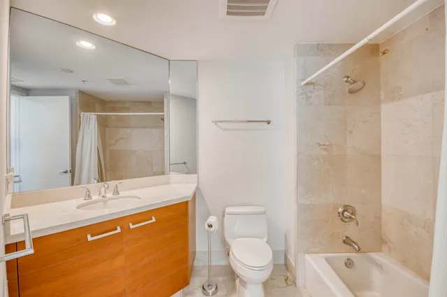 a bathroom with a granite countertop sink toilet and shower