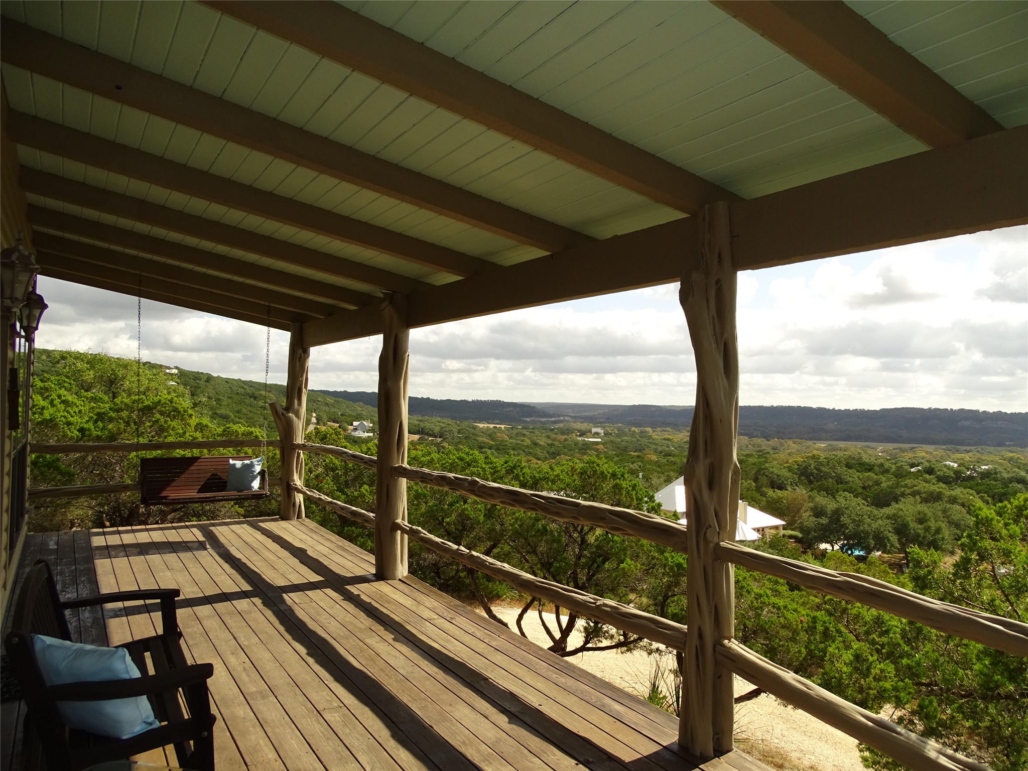 919 Little Ranches Road Wimberley, TX 78676 - Photo 3 of 13 A spacious wooden deck provides sweeping views of the verdant valley, perfect for outdoor enjoyment.