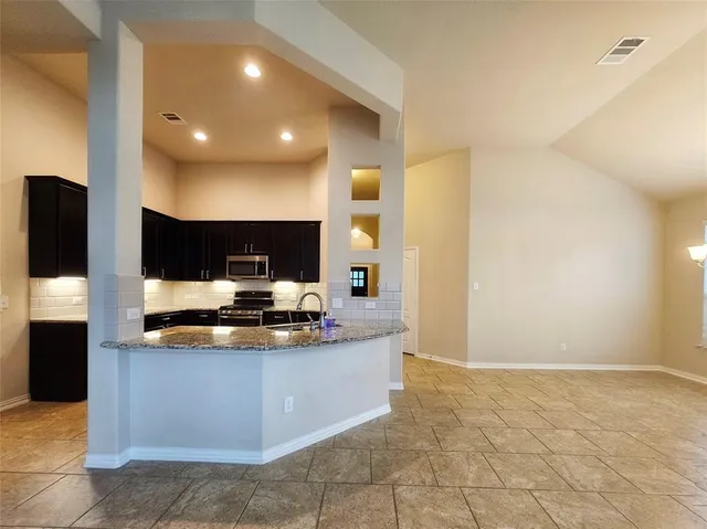 a view of a kitchen with stainless steel appliances granite countertop a sink and a stove