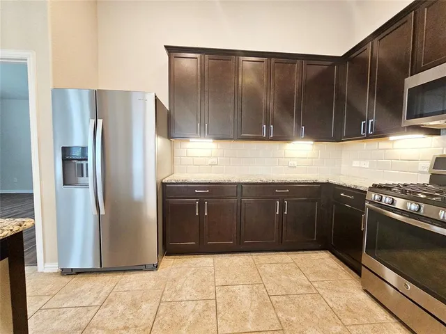 a kitchen with granite countertop a refrigerator and a stove top oven