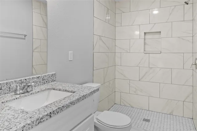 a bathroom with a granite countertop bathtub sink mirror toilet and shower