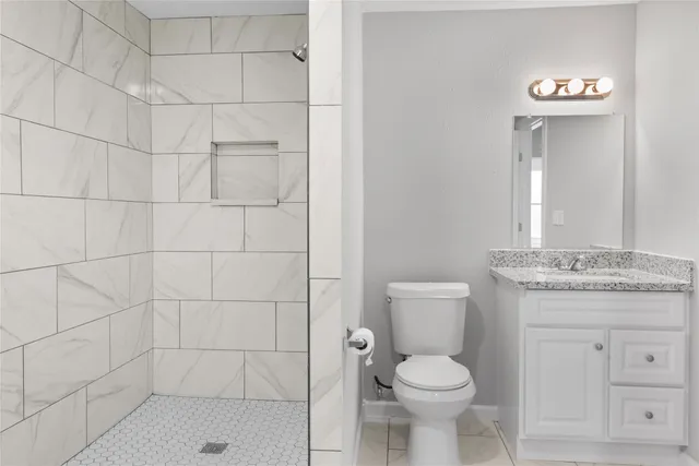 a bathroom with a granite countertop toilet a sink and mirror