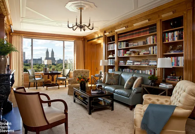 a living room with furniture a bookshelf and a large window