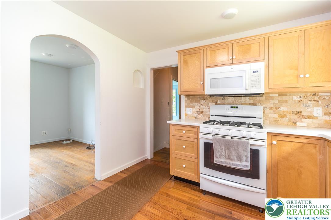 1815 Leithsville Road Hellertown, PA 18055 - Photo 6 of 38 A well-equipped kitchen boasts light wood cabinetry and a tile backsplash, seamlessly connecting to an adjoining room with an arched doorway.