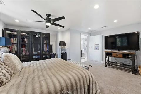 a spacious bedroom with a bed a mirror and a flat tv screen on a dresser