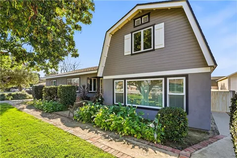 a front view of a house with a garden and trees