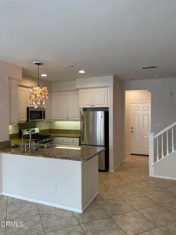 a kitchen with stainless steel appliances granite countertop a sink and a refrigerator
