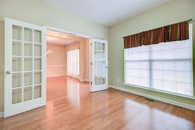 an empty room with wooden floor mirror and windows