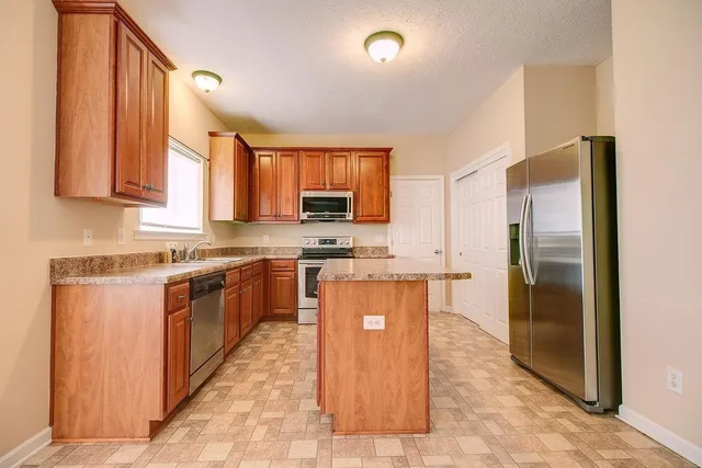 a kitchen with stainless steel appliances granite countertop a sink stove microwave and refrigerator