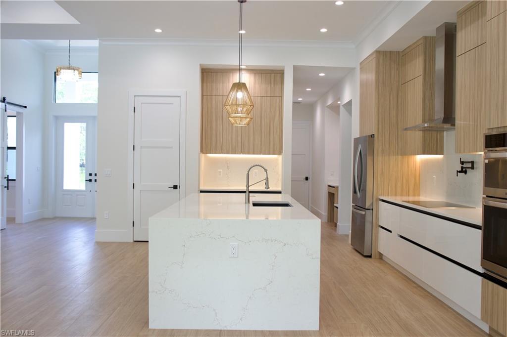 428 21st Street Southwest Naples, FL 34117 - Photo 20 of 45 a large white kitchen with stainless steel appliances kitchen island a large counter top and a refrigerator