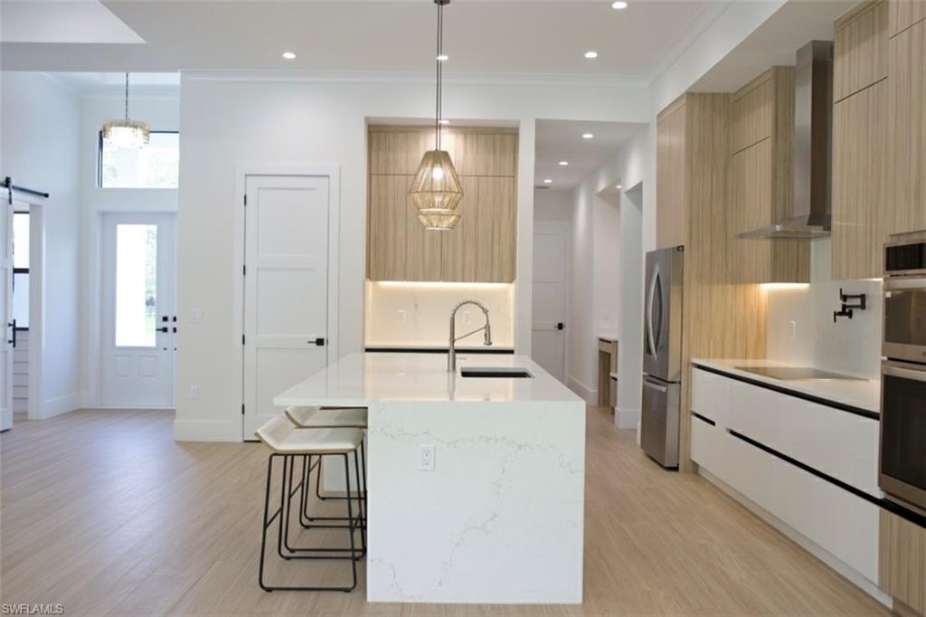 428 21st Street Southwest Naples, FL 34117 - Photo 21 of 45 a large white kitchen with lots of counter space a refrigerator a sink and a stove