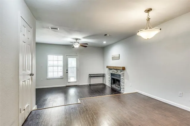 an empty room with wooden floor fireplace and windows