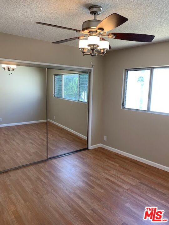 1201 South Sherbourne Drive, Unit 4 Los Angeles, CA 90035 - Photo 13 of 14 an empty room with wooden floor chandelier fan and windows