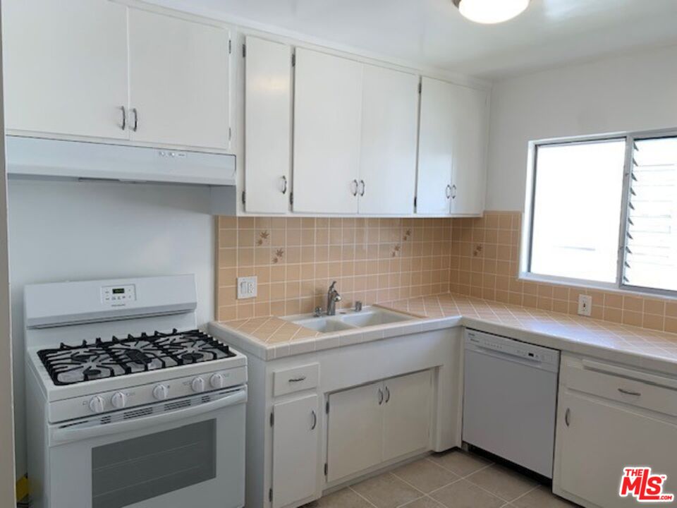 1201 South Sherbourne Drive, Unit 4 Los Angeles, CA 90035 - Photo 5 of 14 a kitchen with white cabinets and appliances
