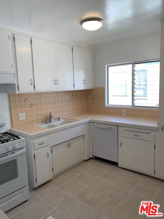 1201 South Sherbourne Drive, Unit 4 Los Angeles, CA 90035 - Photo 6 of 14 a kitchen with white cabinets appliances and a window