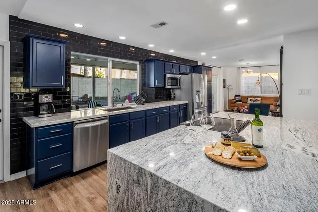 a kitchen with stainless steel appliances granite countertop a sink a stove and a refrigerator