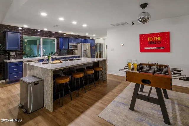 a kitchen with stainless steel appliances kitchen island granite countertop a table chairs sink and cabinets