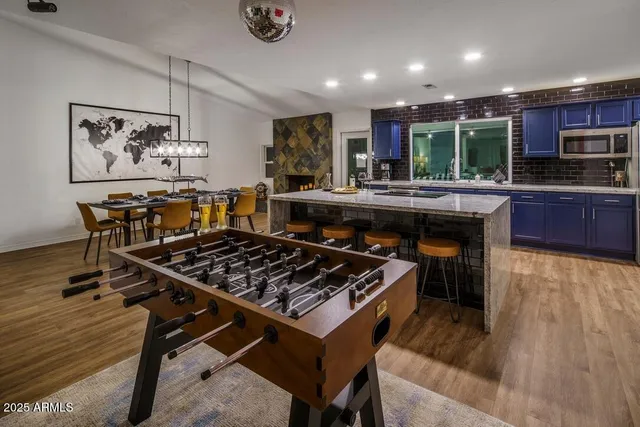 a kitchen with stainless steel appliances granite countertop a stove a refrigerator a sink a dining table and chairs with wooden floor