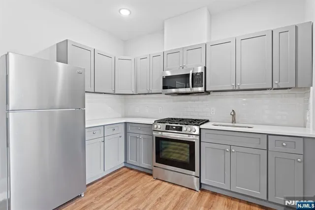 a kitchen with cabinets stainless steel appliances and wooden floor