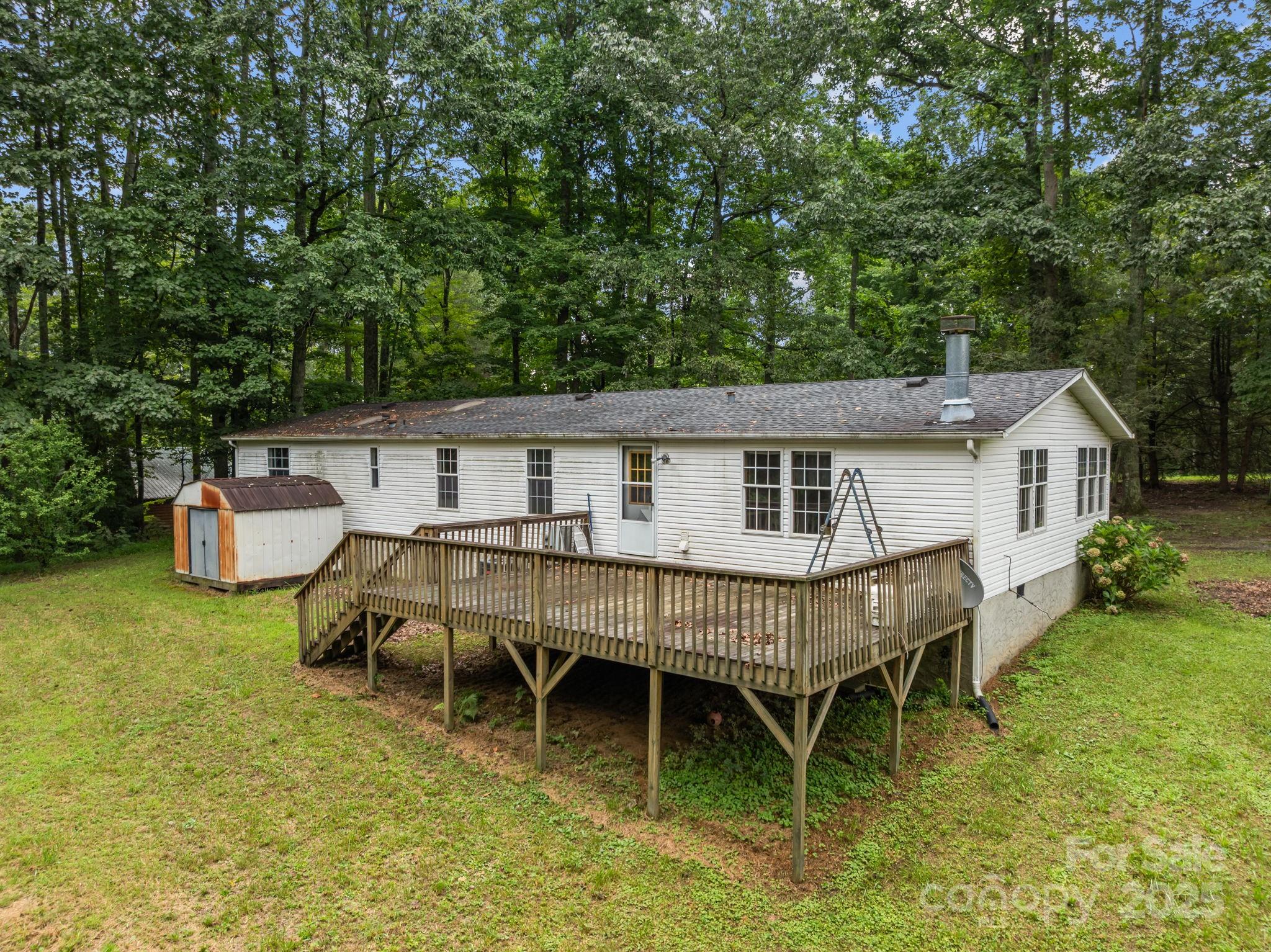 573 Deep Gap Loop Road Flat Rock, NC 28731 - Photo 2 of 20 a roof deck with table and chairs and potted plants with large trees