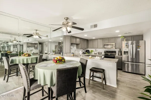 a kitchen with stainless steel appliances kitchen island granite countertop a dining table chairs and white cabinets