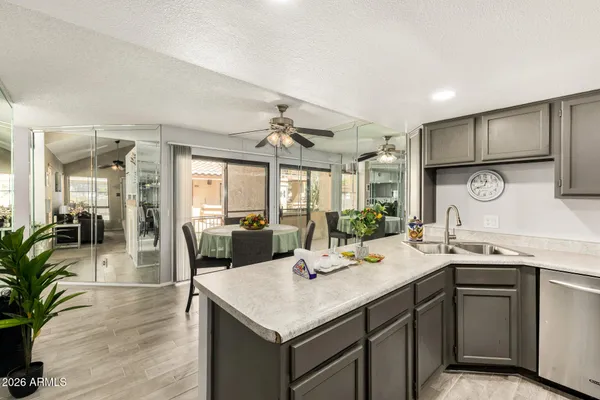 a kitchen with a sink dishwasher a dining table and chairs with wooden floor
