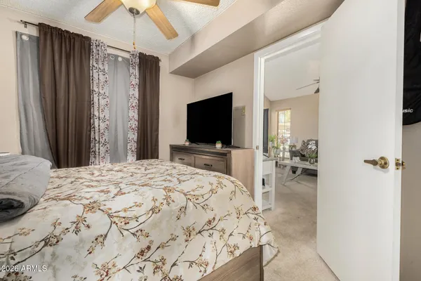 a bedroom with a bed and a flat tv screen on dresser