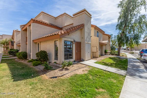 a view of a house with small yard plants and palm trees