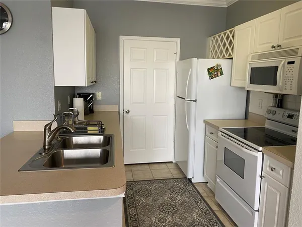 a kitchen with a refrigerator sink and white cabinets