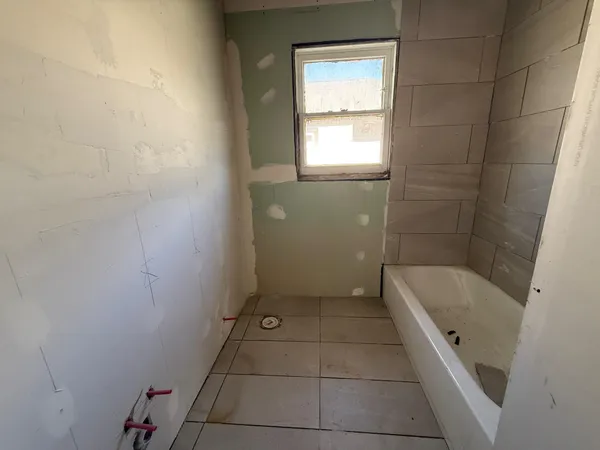 a bathroom with a tub a sink a window and a shower