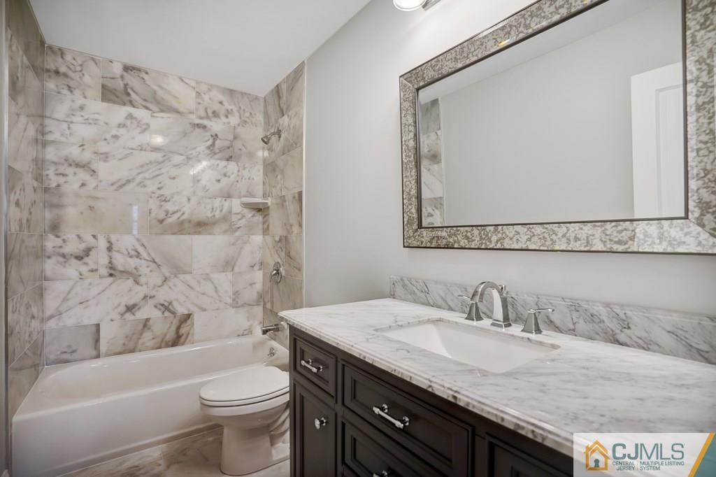 17 Greenbrook Road Middlesex, NJ 08846 - Photo 18 of 24 a bathroom with a granite countertop sink a toilet a mirror and bathtub