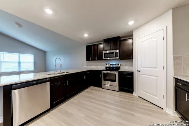 a large kitchen with cabinets stainless steel appliances and a window