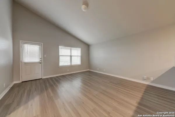 an empty room with wooden floor and windows