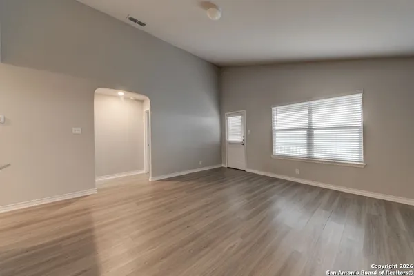 an empty room with wooden floor and windows