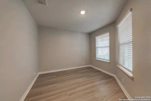 an empty room with wooden floor and windows