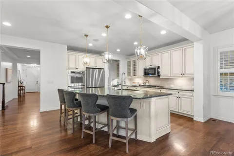 a kitchen with stainless steel appliances granite countertop a kitchen island and chairs in it