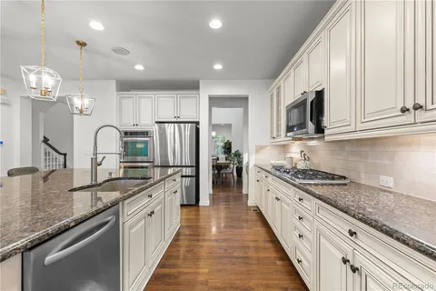 a large kitchen with granite countertop a large stove top oven a sink a counter space and cabinets